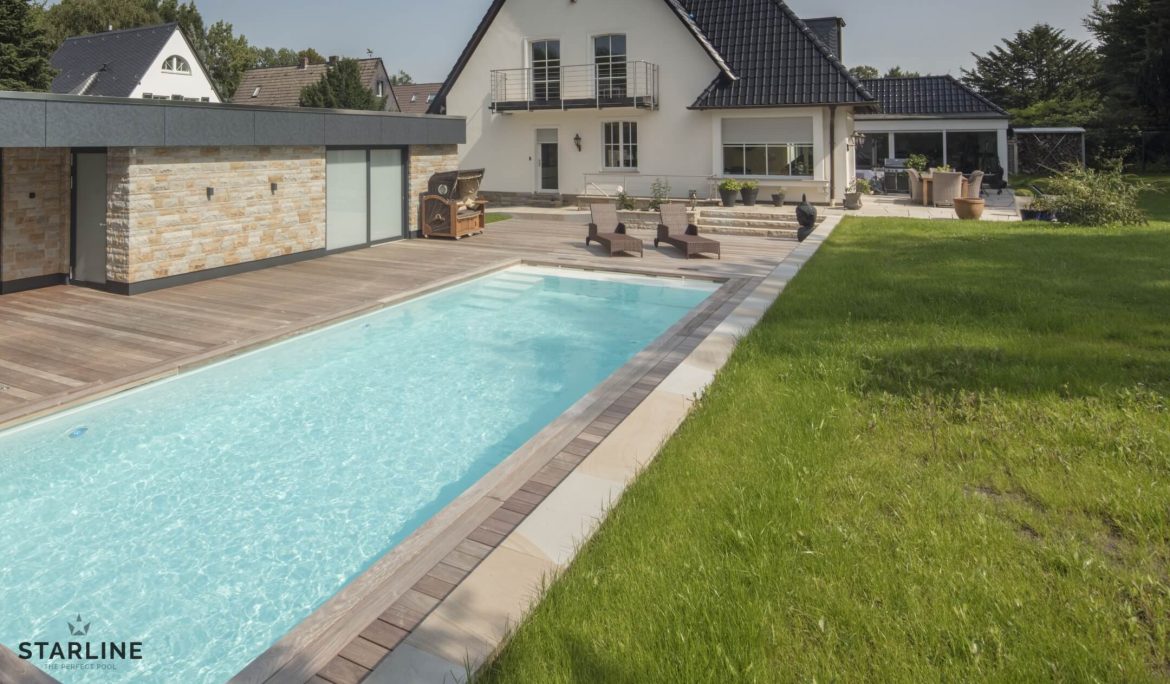 Fertigpool im Vordergrund mit Rasen und Haus im Hintergrund