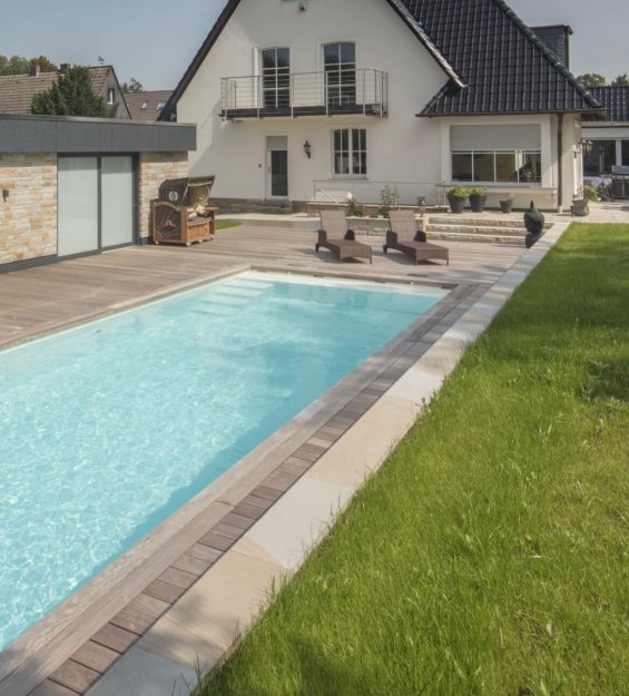Fertigpool im Vordergrund mit Rasen und Haus im Hintergrund