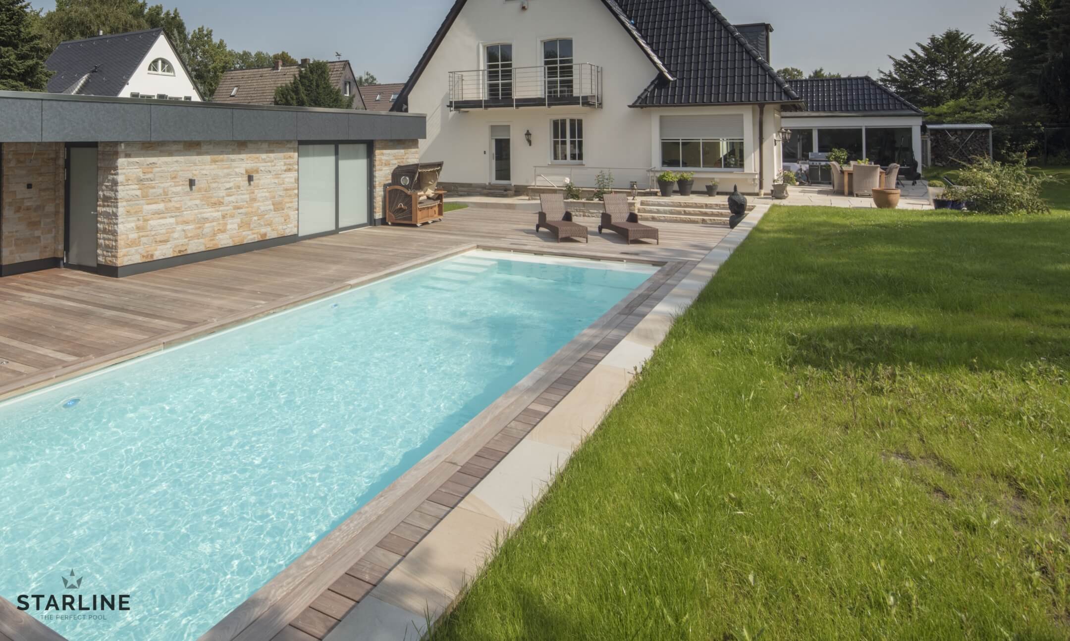 Fertigpool im Vordergrund mit Rasen und Haus im Hintergrund