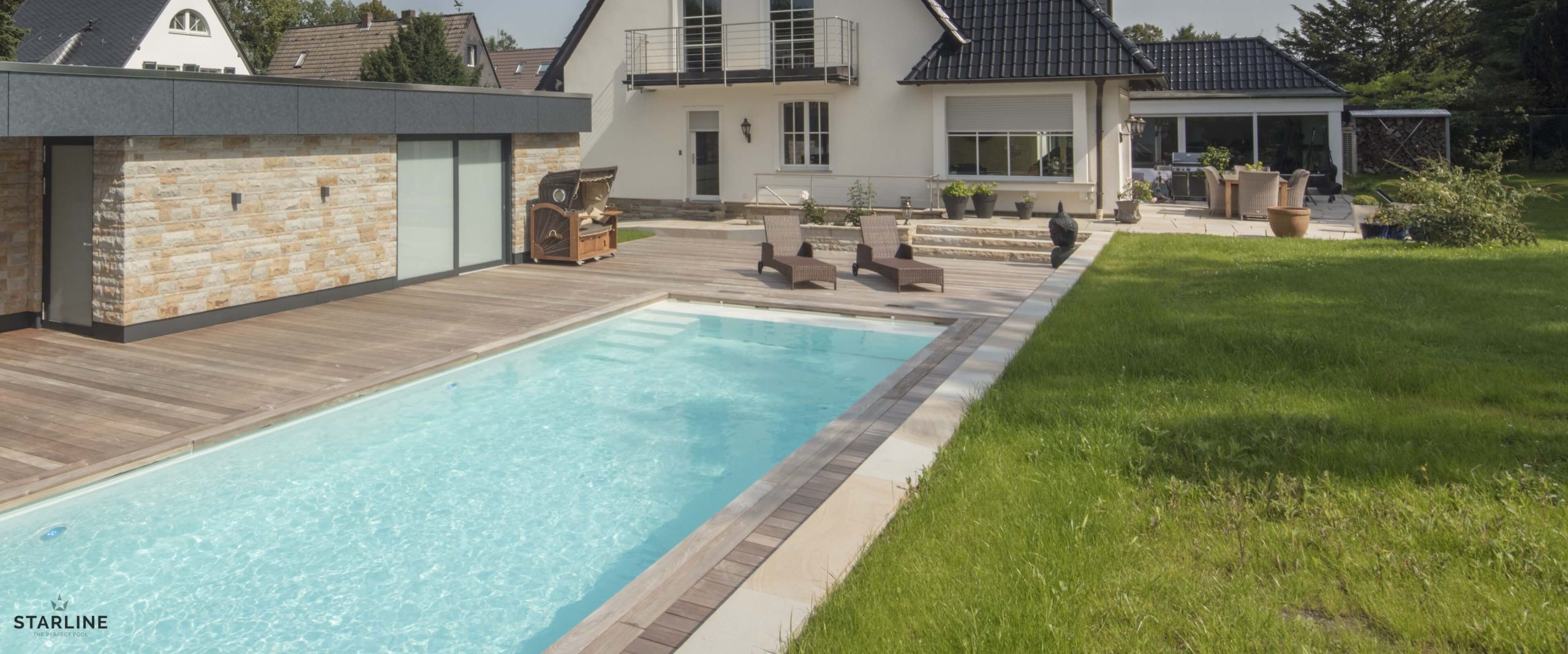 Fertigpool GFK Pool mit Rasenfläche im Vordergrund , hinten Haus, links Garage davor ein Strandkorb
