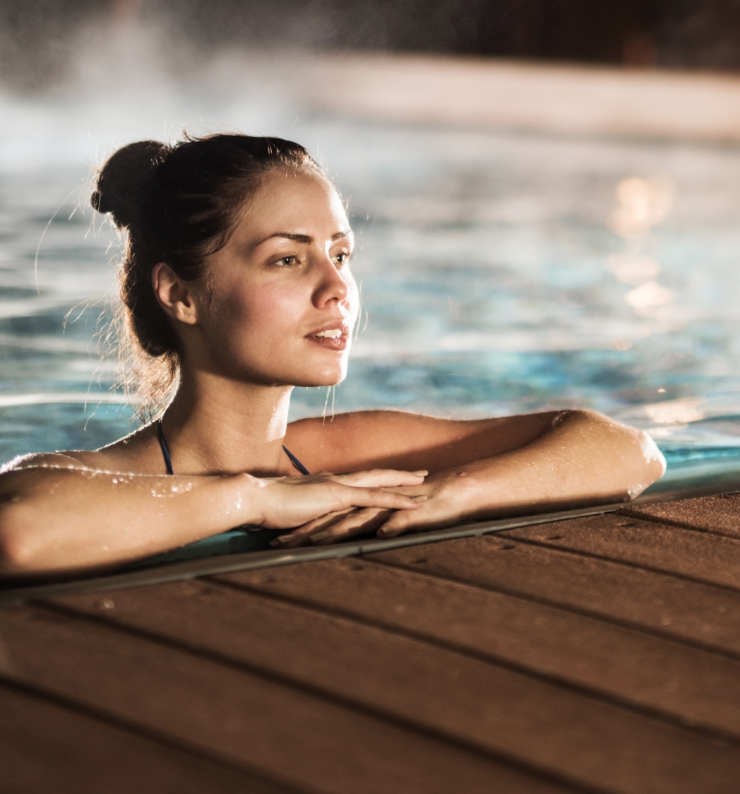 Frau von Vorne am Pool stützt sich auf Poolrand ab