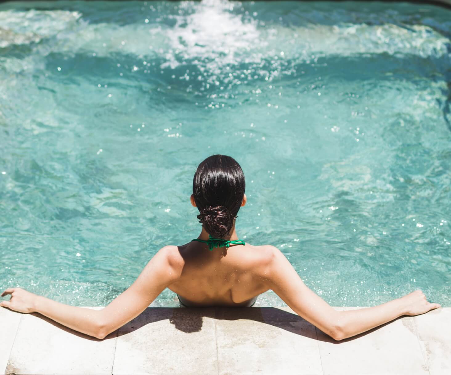 Frau von hinten am Beckenrand im Whirlpool